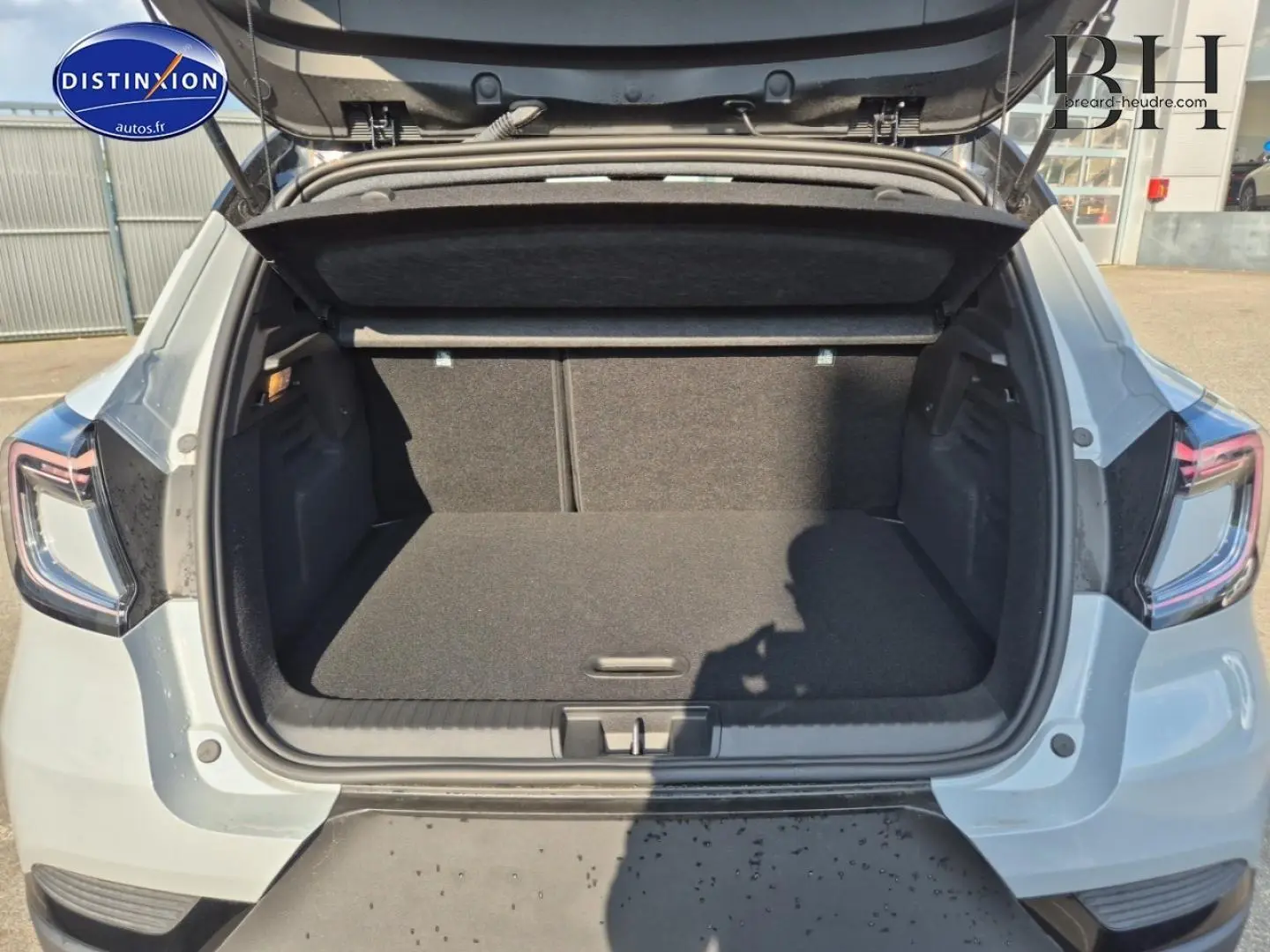 Coffre ouvert vu de l'arrière d'un Renault Captur 2025 bleu Iron métallisé avec feux arrière LED visibles.