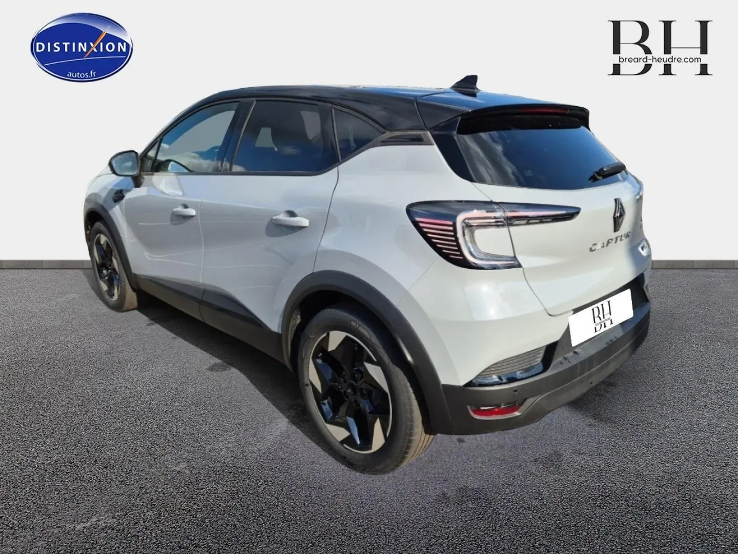 Vue 3/4 arrière gauche d'un Renault Captur 2025 blanc avec toit noir et jantes noires distinctives.