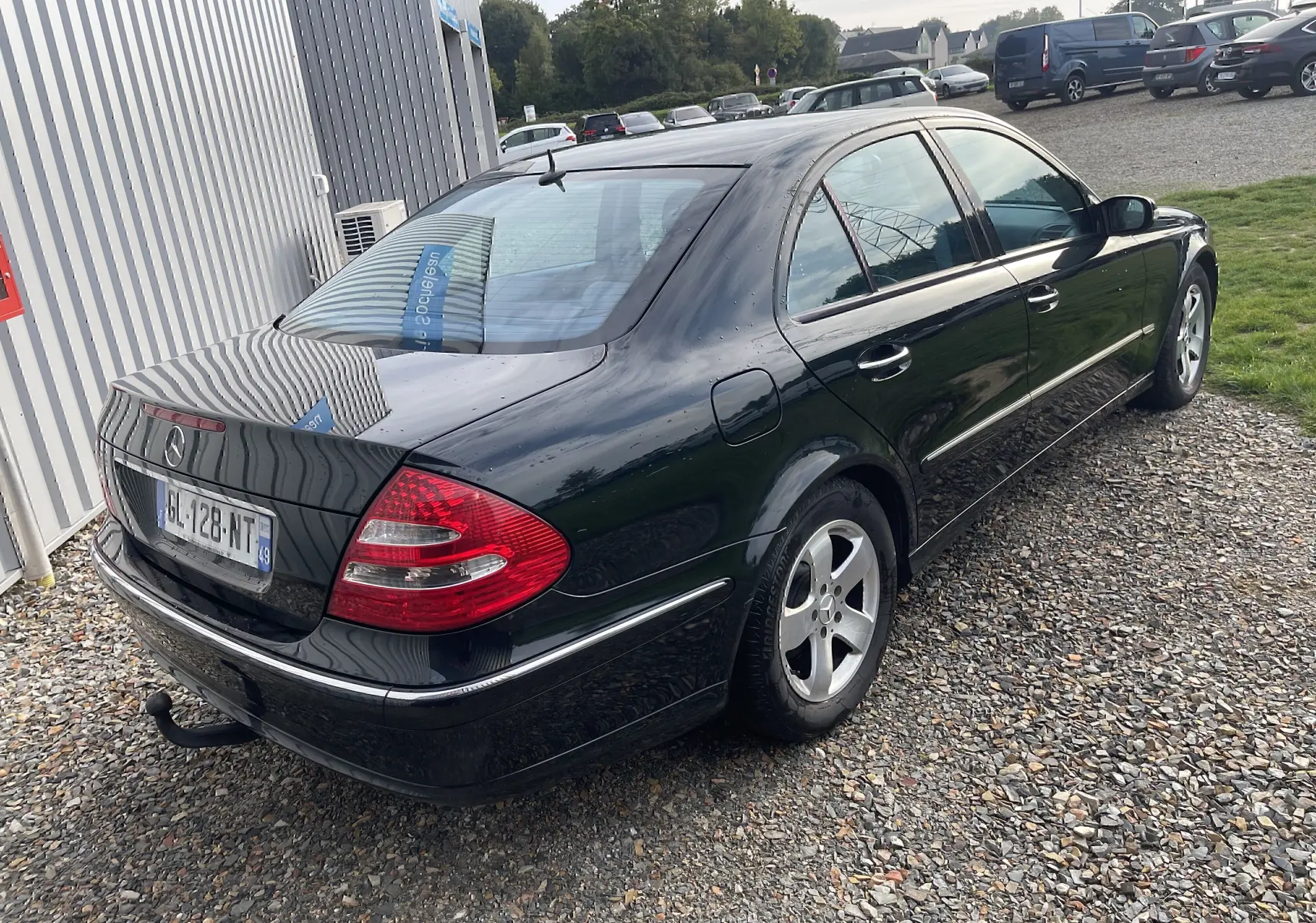 Vue 3/4 arrière droite d'une Mercedes Classe E 320 CDI Elegance noire de 2003 avec attelage et jantes alliage.