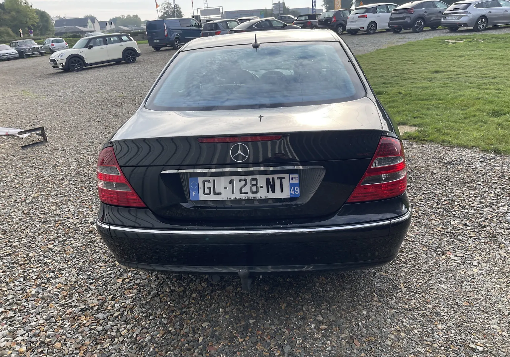Vue arrière d'une Mercedes Classe E 320 CDI noire de 2003 avec feux arrière rouges et attelage visible.