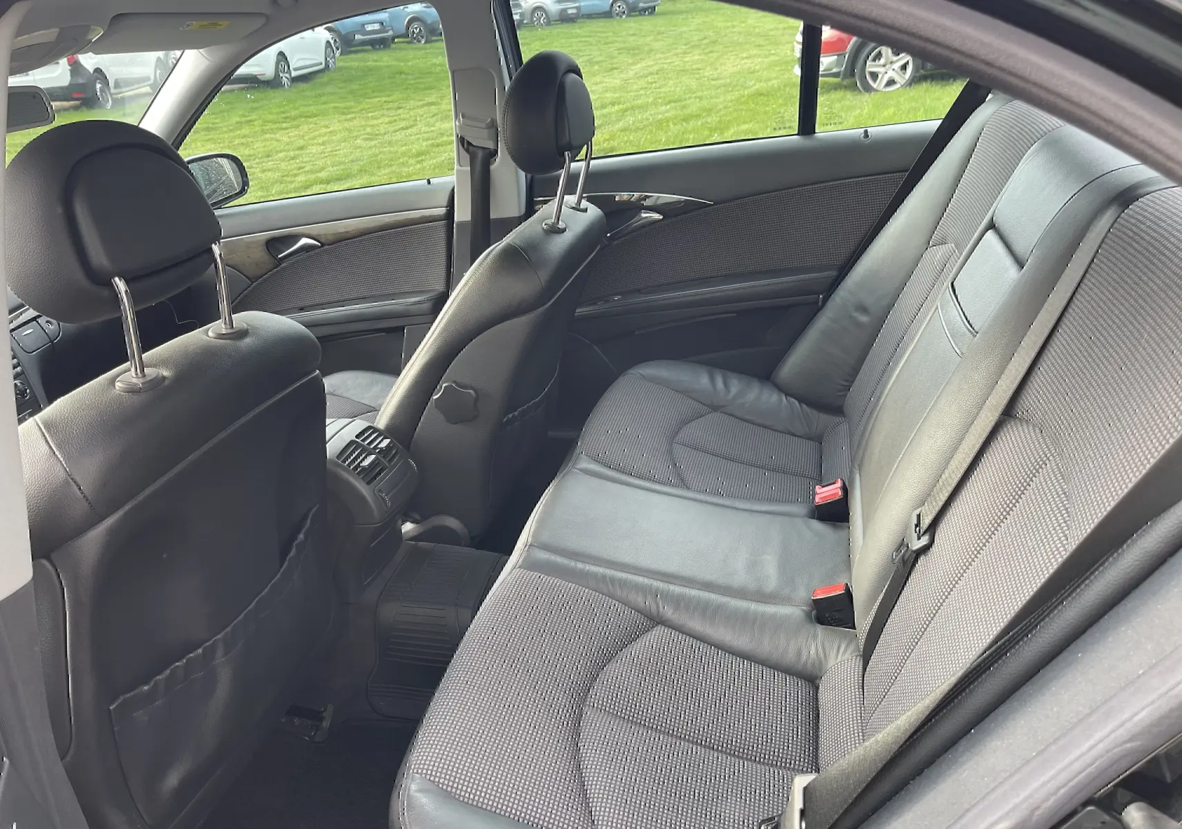 Vue intérieure côté droit montrant la banquette arrière en tissu et cuir gris d'une Mercedes Classe E noire de 2003.