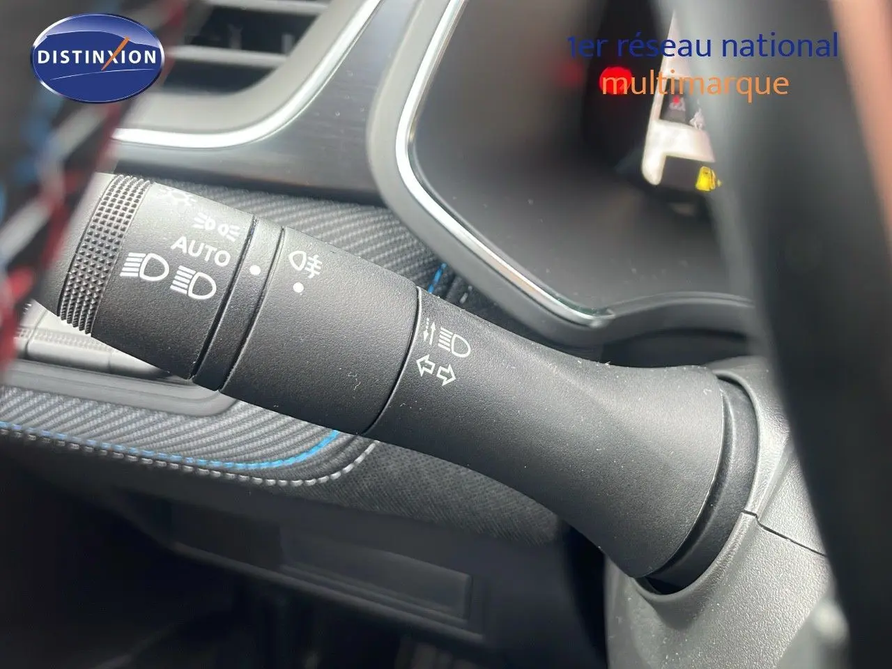 Gros plan sur la commande des phares et clignotants du Renault Captur E-Tech gris cassiopée avec surpiqûres bleues.