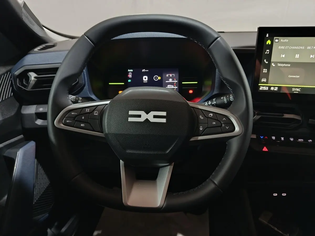 Vue centrée sur le volant noir du Dacia Bigster 2025 avec tableau de bord numérique et écran tactile à droite.