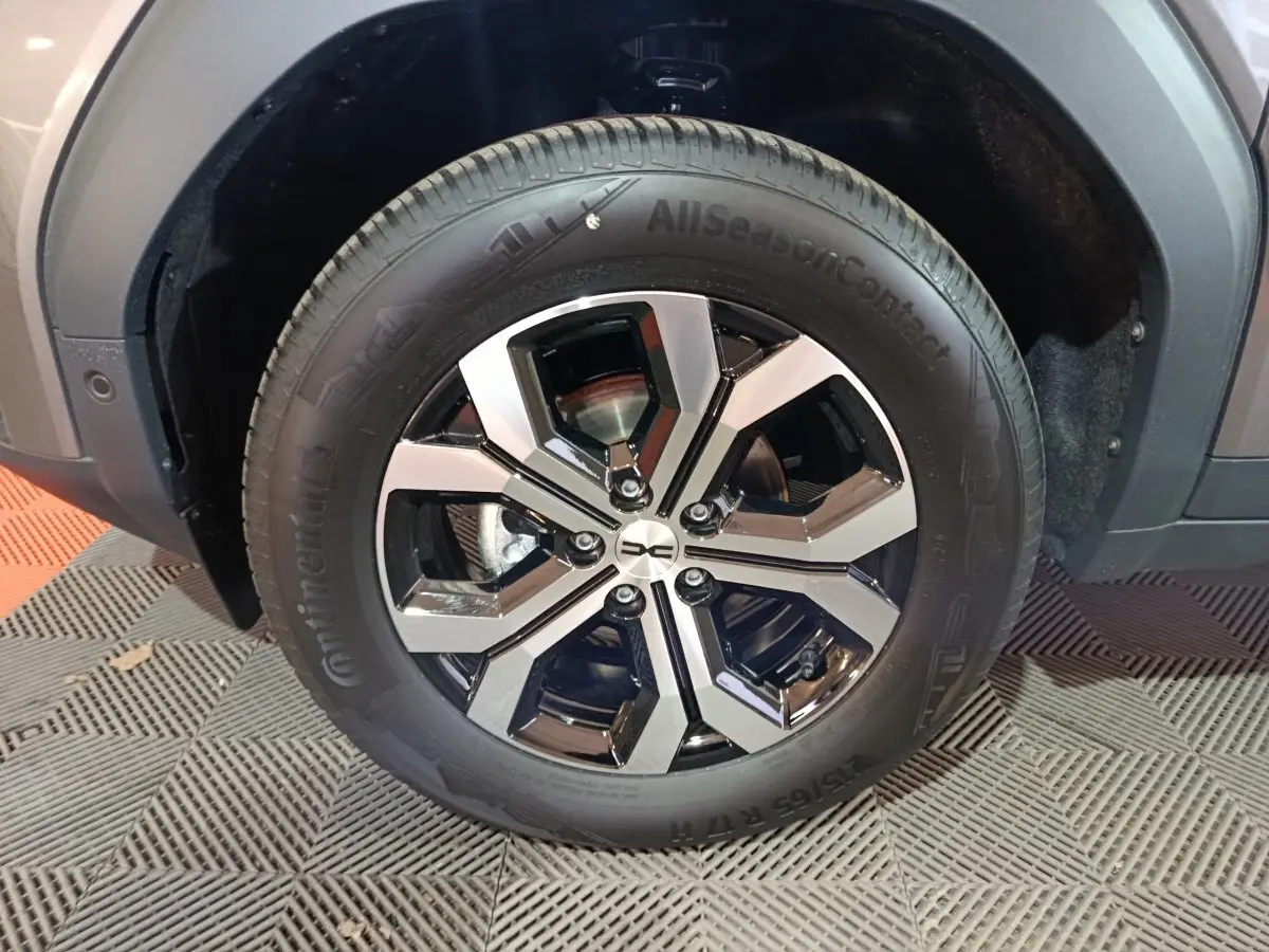 Gros plan sur la roue avant droite du Dacia Bigster gris foncé, mettant en valeur la jante noire et argentée au design moderne.