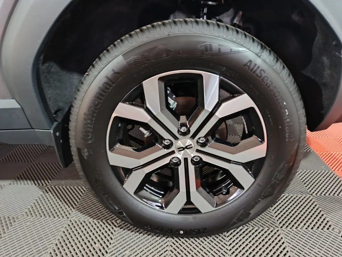 Gros plan sur la roue avant droite du Dacia Bigster gris foncé, mettant en valeur la jante noire et argentée au design moderne.