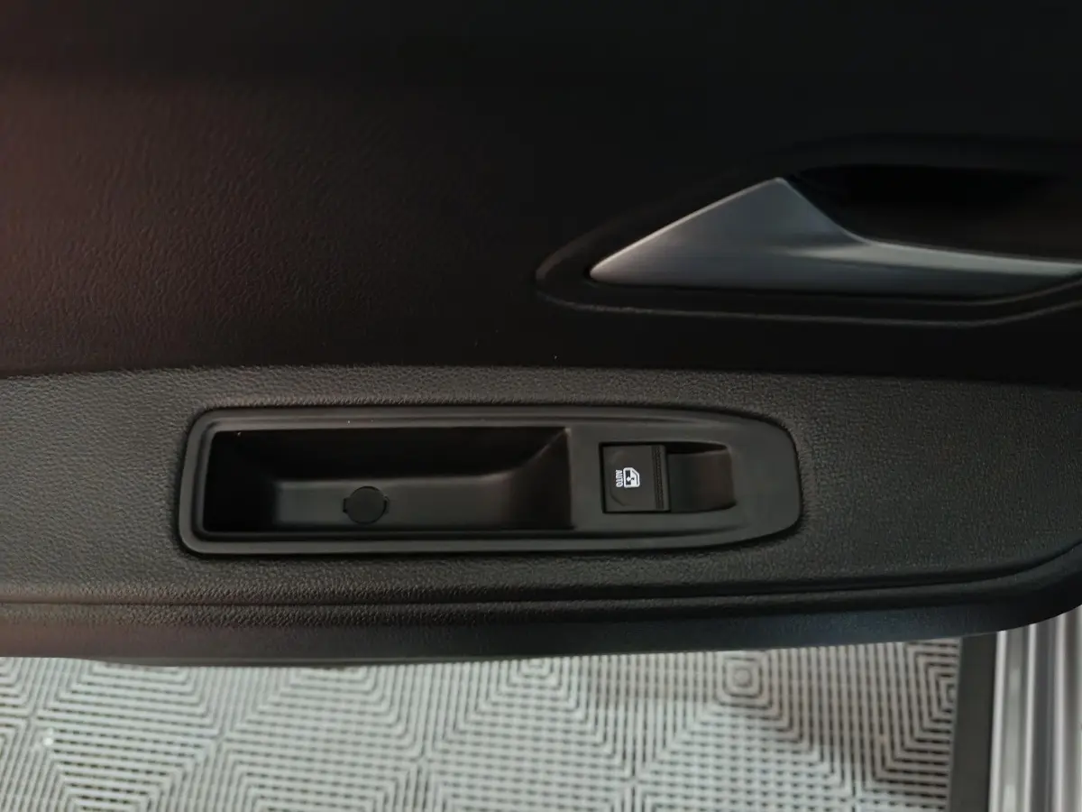 Détail de la commande de lève-vitre côté conducteur sur la porte intérieure d'une Dacia Bigster gris foncé.