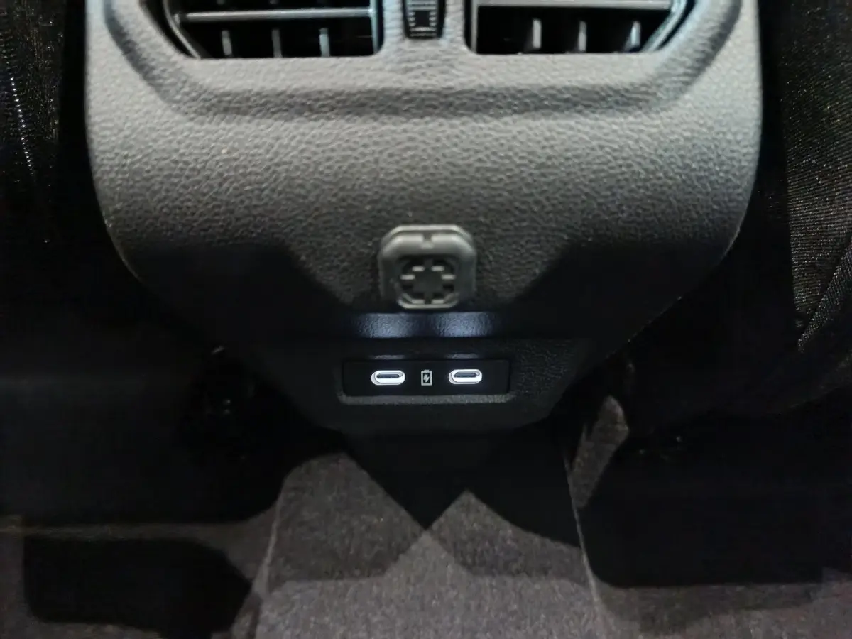 Vue rapprochée des ports USB-C arrière illuminés sur la console centrale noire du Dacia Bigster gris foncé.
