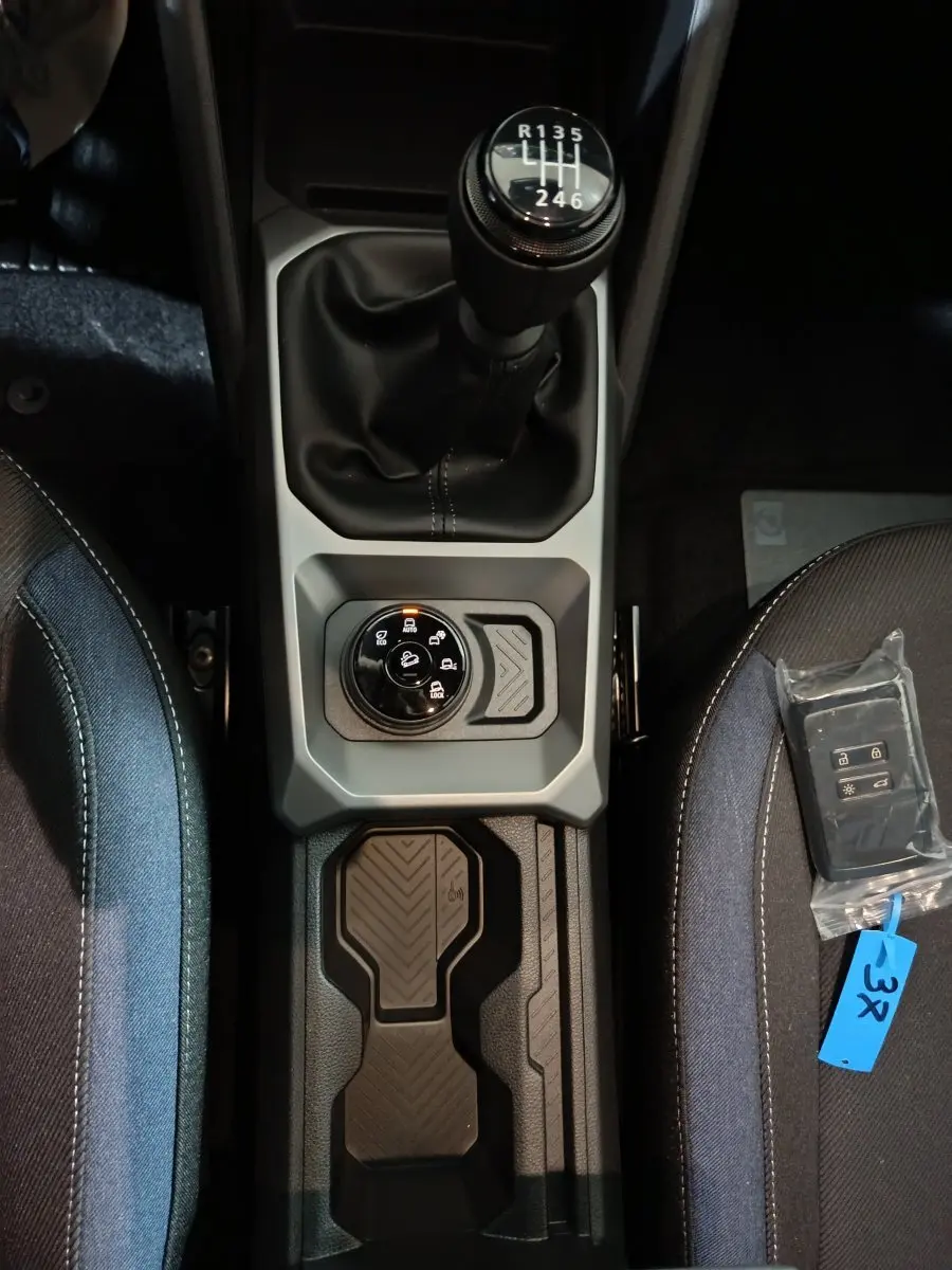 Vue plongeante sur la console centrale du Dacia Bigster 2025, avec levier de vitesses manuel et sélecteur de modes de conduite.