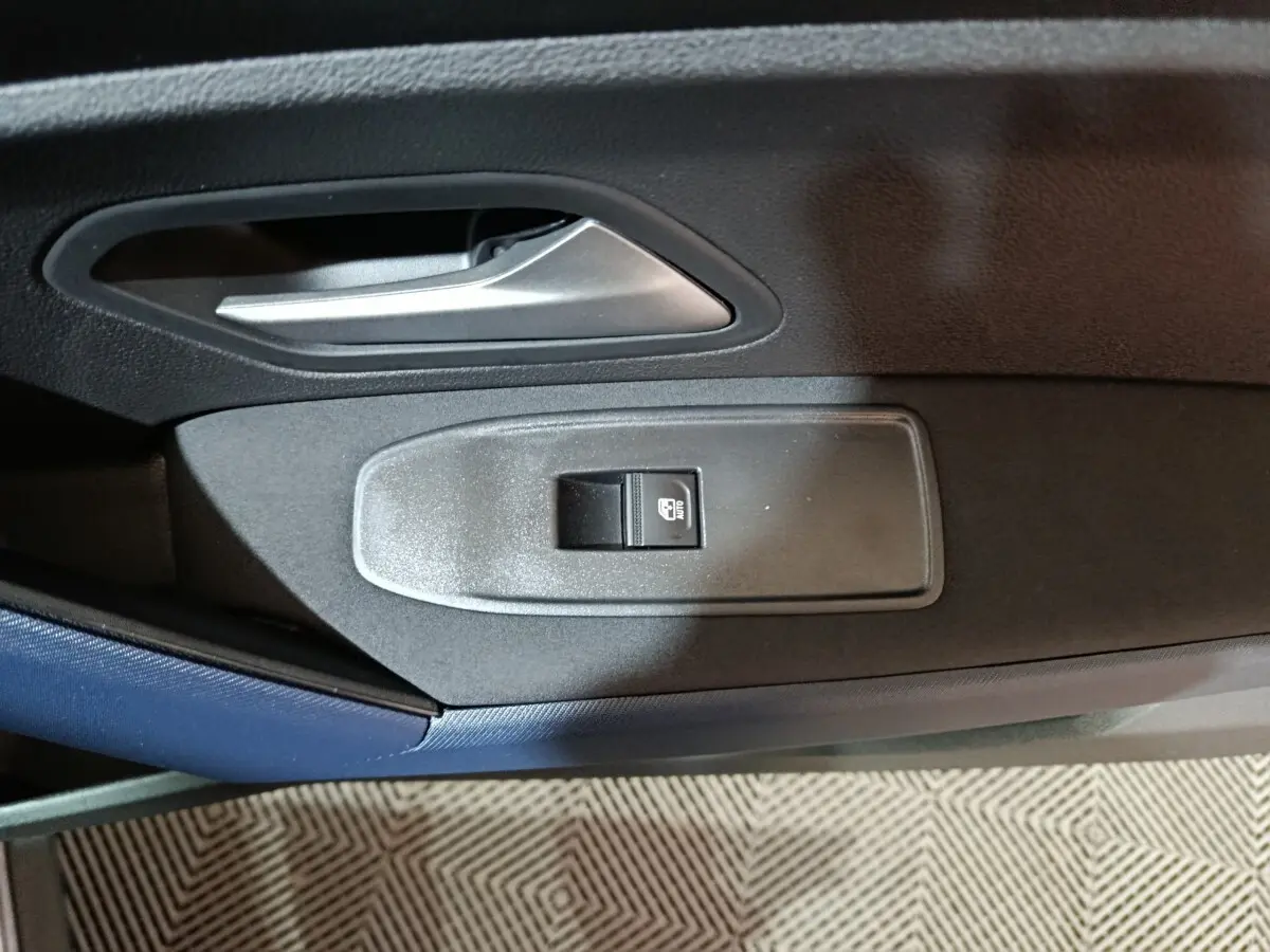 Gros plan sur la poignée intérieure et le bouton de verrouillage de la porte côté conducteur du Dacia Bigster gris foncé.