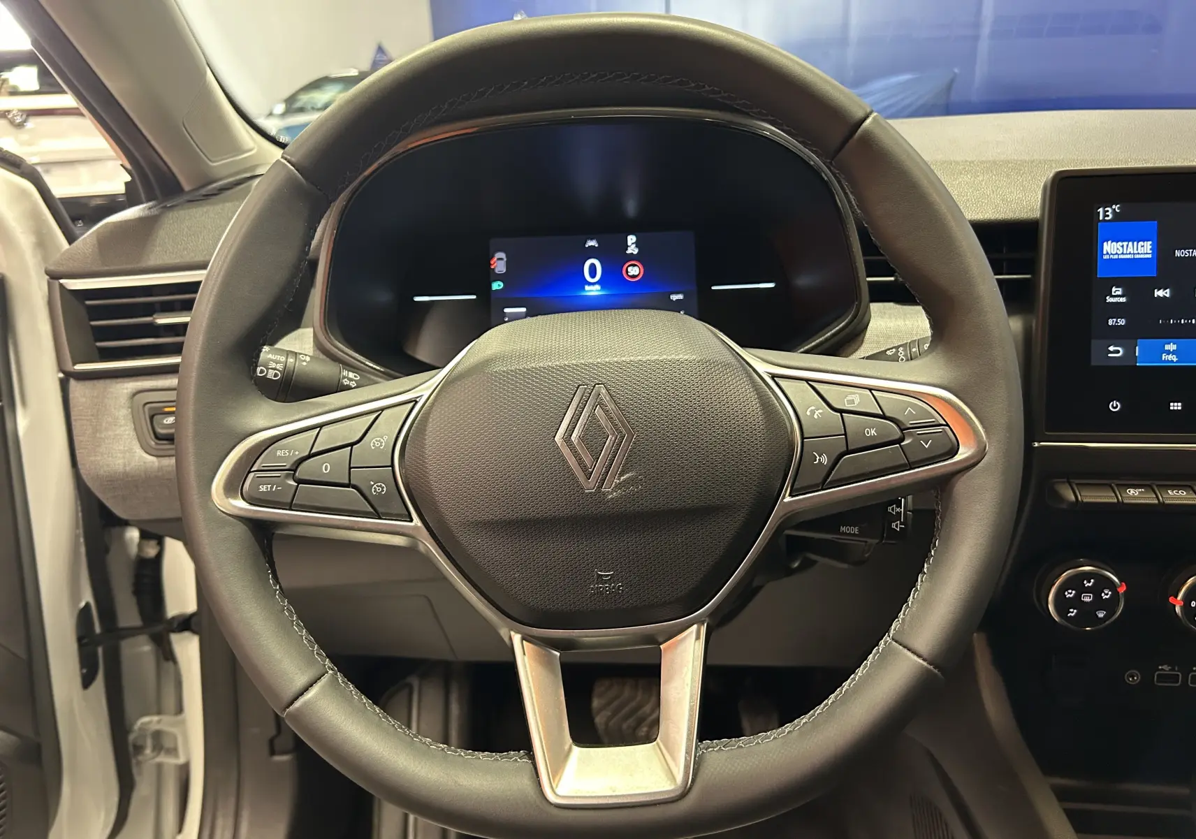 Vue rapprochée du volant noir de la Renault Clio V 2025 avec tableau de bord digital et écran central tactile.