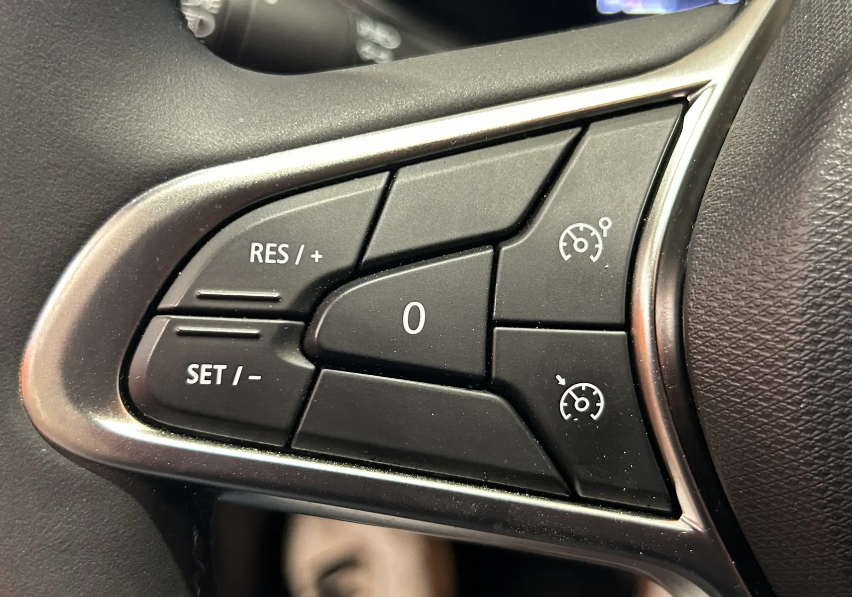 Gros plan sur les commandes de régulateur de vitesse au volant noir de la Renault Clio V TCE 90ch.