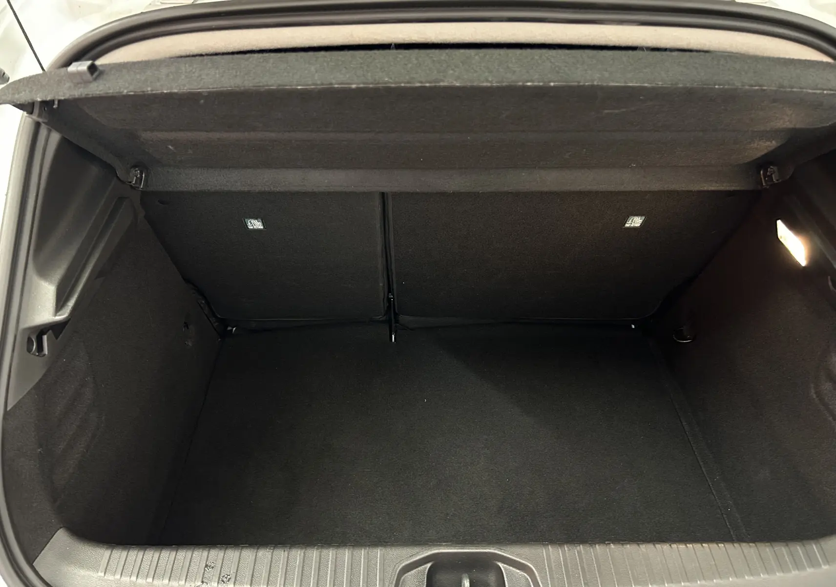 Coffre ouvert vu de face d'une Renault Clio V blanche, montrant un espace de rangement propre et vide.