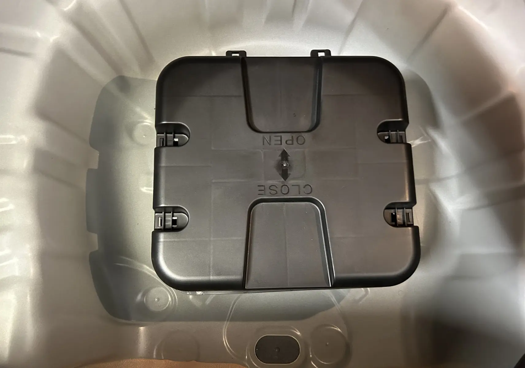 Vue plongeante sur le coffre blanc d'une Renault Clio V 2025, montrant un compartiment de rangement noir fermé.