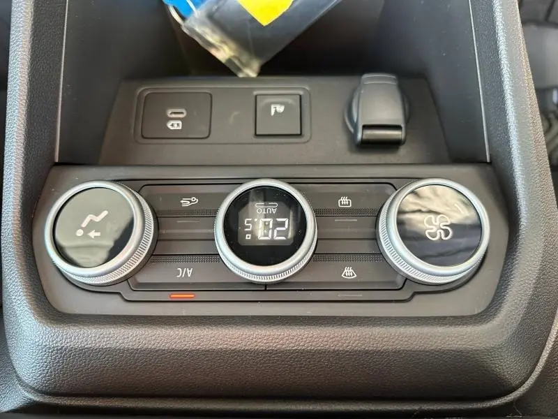 Gros plan sur les commandes de climatisation du Dacia Jogger blanc, affichage digital et boutons rotatifs noirs.