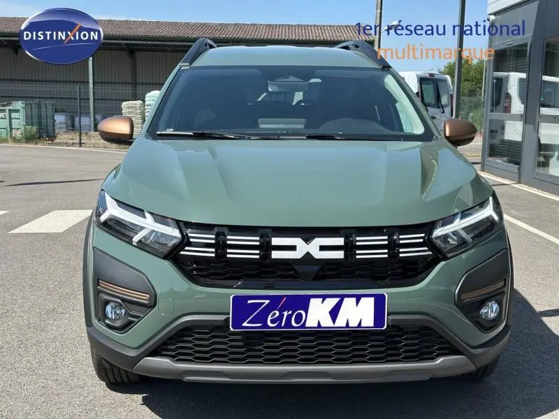 Vue avant d'un Dacia Jogger vert avec rétroviseurs bronze et calandre noire distinctive, en extérieur sur parking.