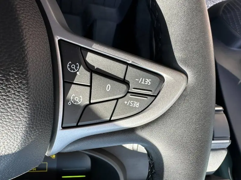 Gros plan sur les commandes de régulateur de vitesse au volant du Dacia Jogger blanc, côté gauche.