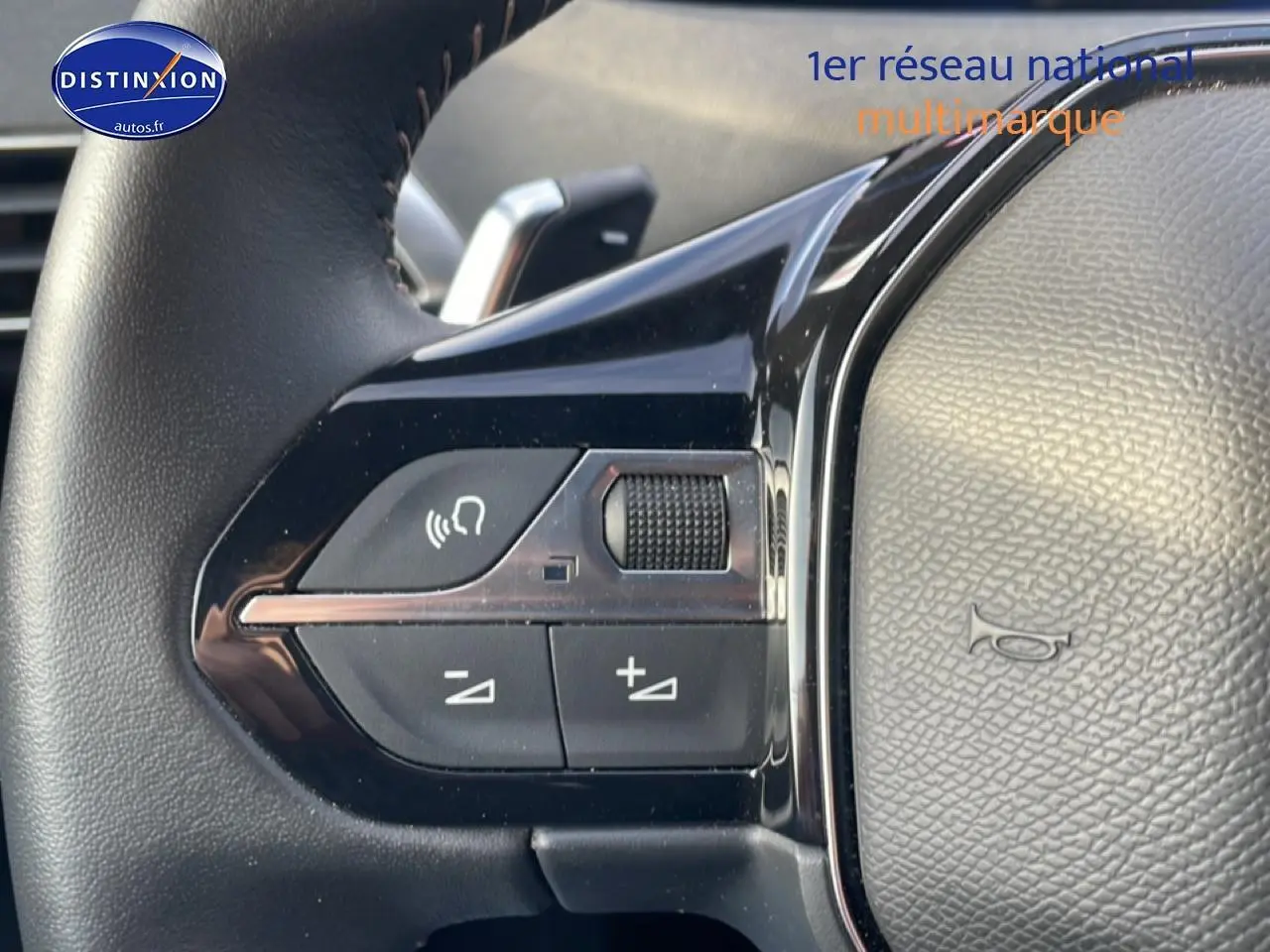 Gros plan sur les commandes vocales et volume au volant cuir noir du Peugeot 3008 bleu Plug-in Hybrid 2024.