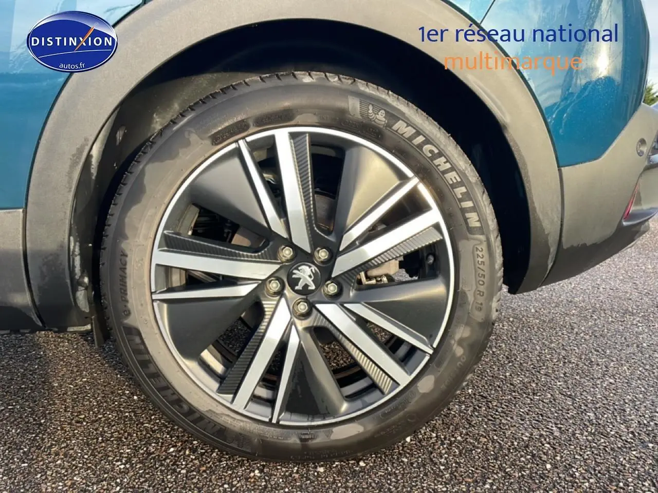 Gros plan sur la roue arrière droite du Peugeot 3008 bleu 2024 avec jante alu et logo lion central.