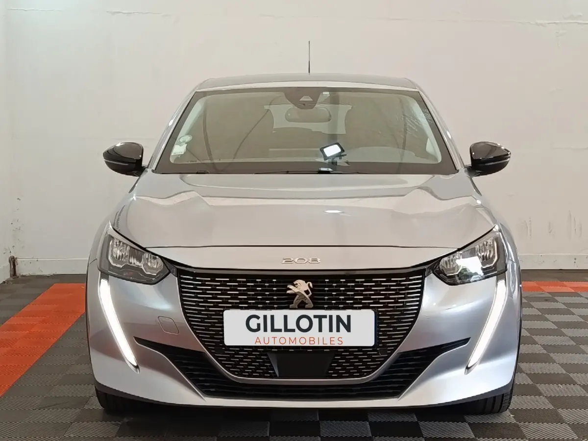 Vue frontale d'une Peugeot 208 Electrique Roadtrip gris clair avec feux LED et calandre noire distinctive.