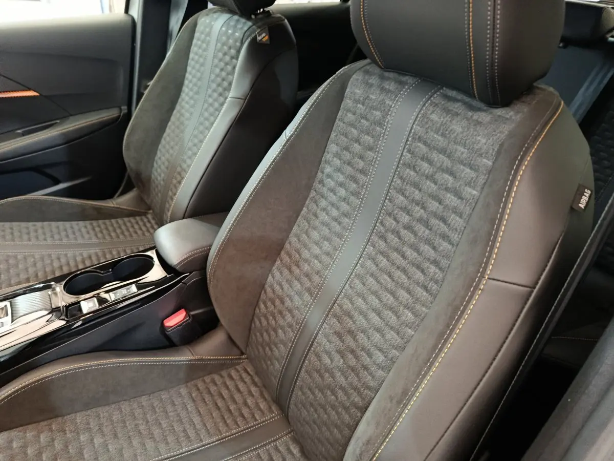 Gros plan sur les sièges avant gris avec surpiqûres orange et détails en cuir du Peugeot 208 Electrique ROADTRIP 2022.