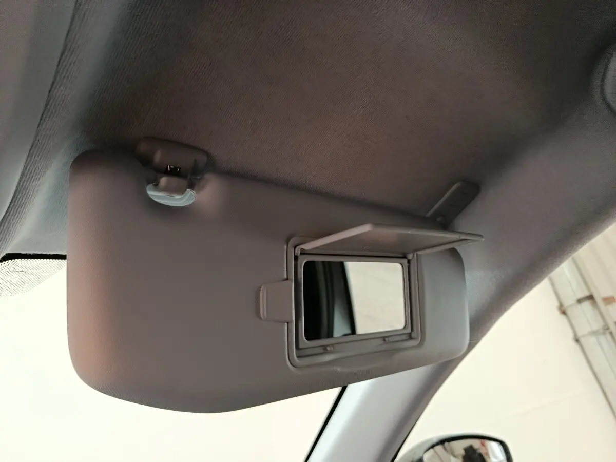 Miroir de courtoisie ouvert sur pare-soleil côté conducteur dans l'habitacle d'une Peugeot 208 électrique gris clair.