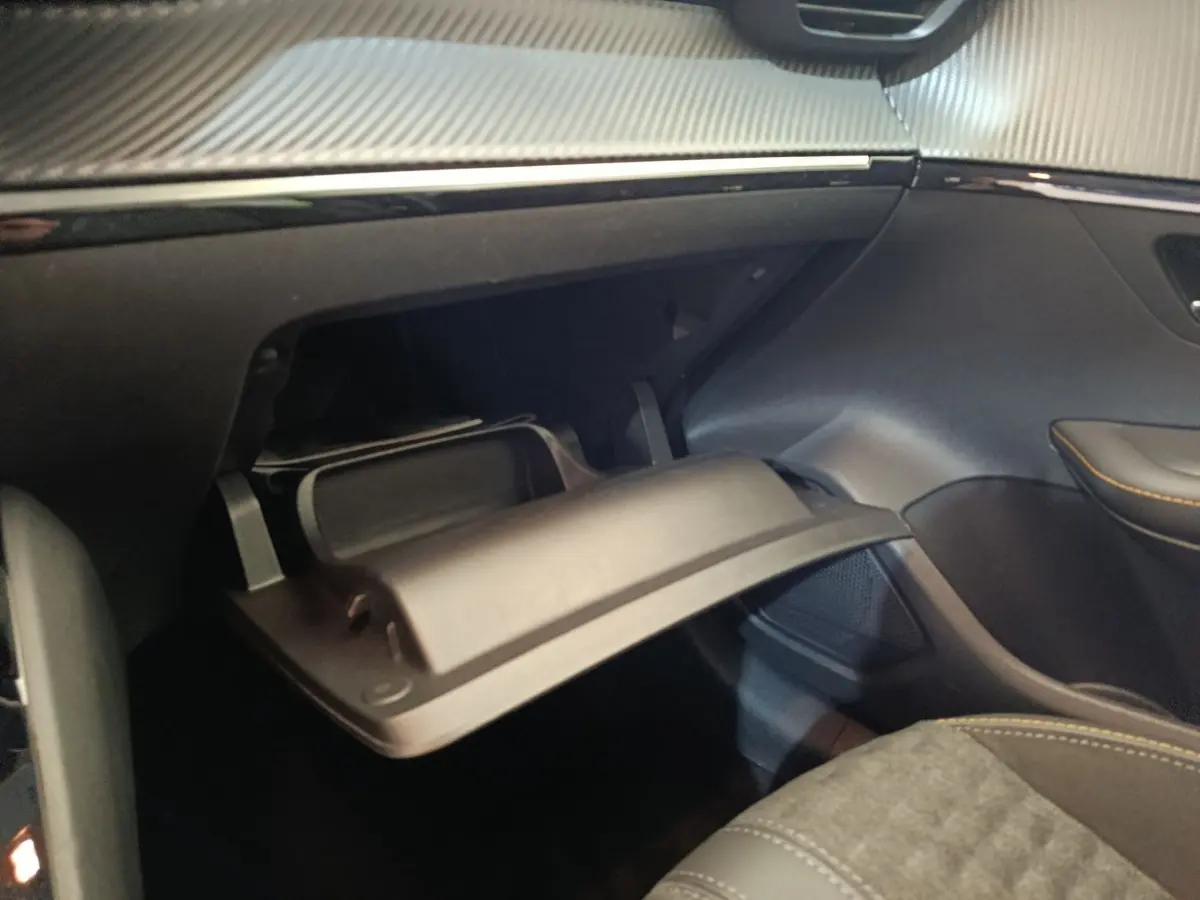 Vue intérieure côté passager du Peugeot 208 électrique gris clair, avec boîte à gants ouverte et détails de sellerie visible.