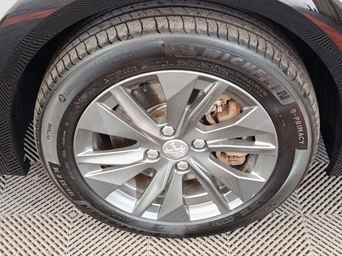 Gros plan sur la roue avant droite grise d'une Peugeot 208 électrique avec jante alliage et pneu Michelin.