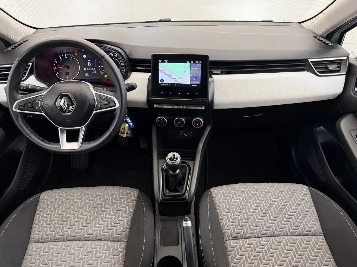Intérieur Renault Clio 2023 vu de face, tableau de bord noir et beige avec écran tactile central et volant cuir noir.