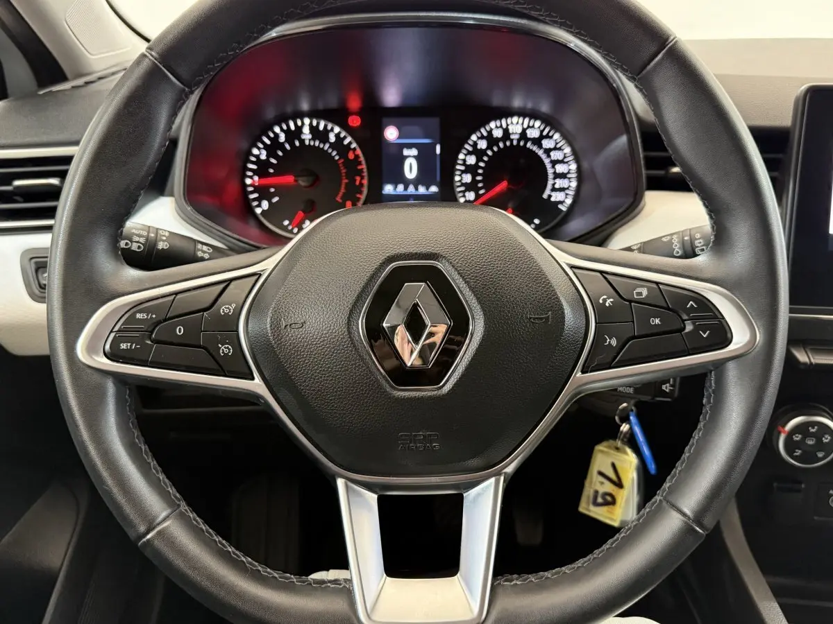 Vue rapprochée du volant cuir noir de la Renault Clio 2023 avec commandes intégrées et tableau de bord éclairé.