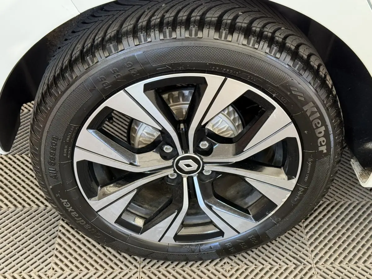Gros plan sur la roue avant droite d'une Renault Clio blanche 2023 avec jante alliage noire et argent.