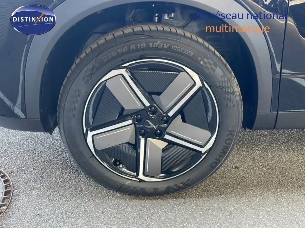 Gros plan sur la roue avant gauche du JAECOO J7 noir carbone métal, mettant en valeur la jante au design géométrique bicolore.