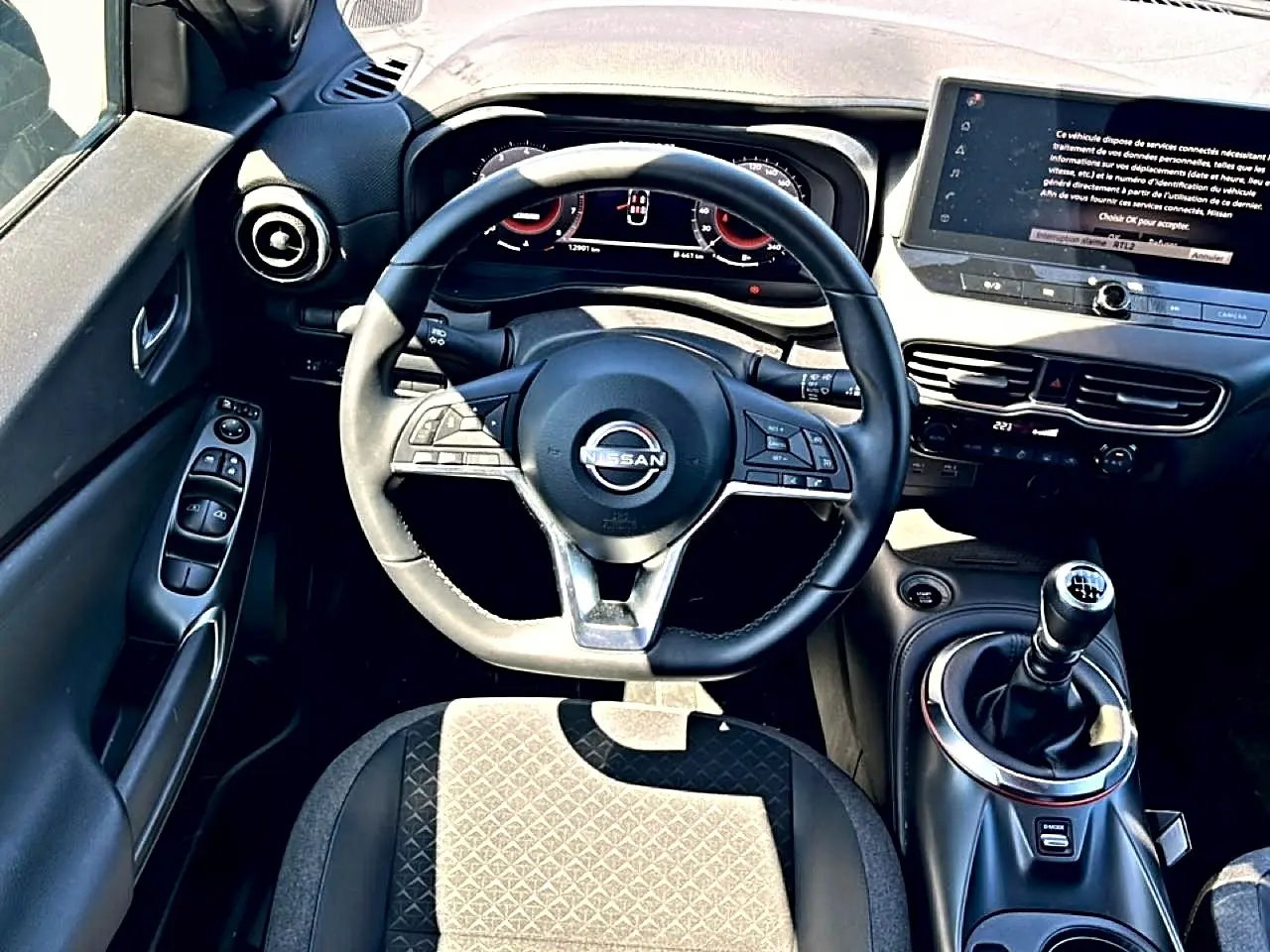 Vue intérieure centrée sur le volant cuir multifonction et levier de vitesse manuel du Nissan Juke gris 2025.
