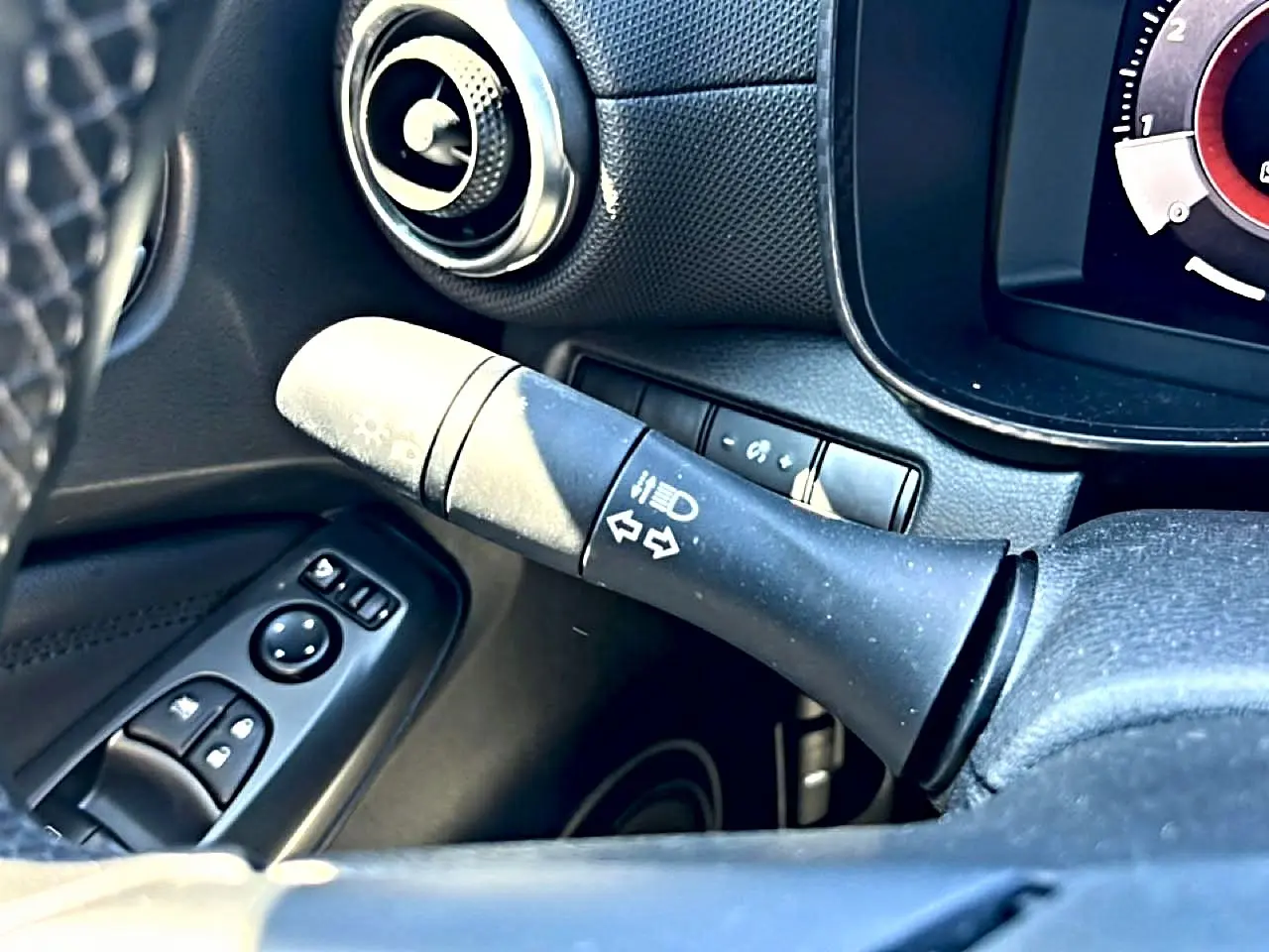 Détail intérieur du levier de clignotant côté gauche du tableau de bord noir du Nissan Juke gris 2025.