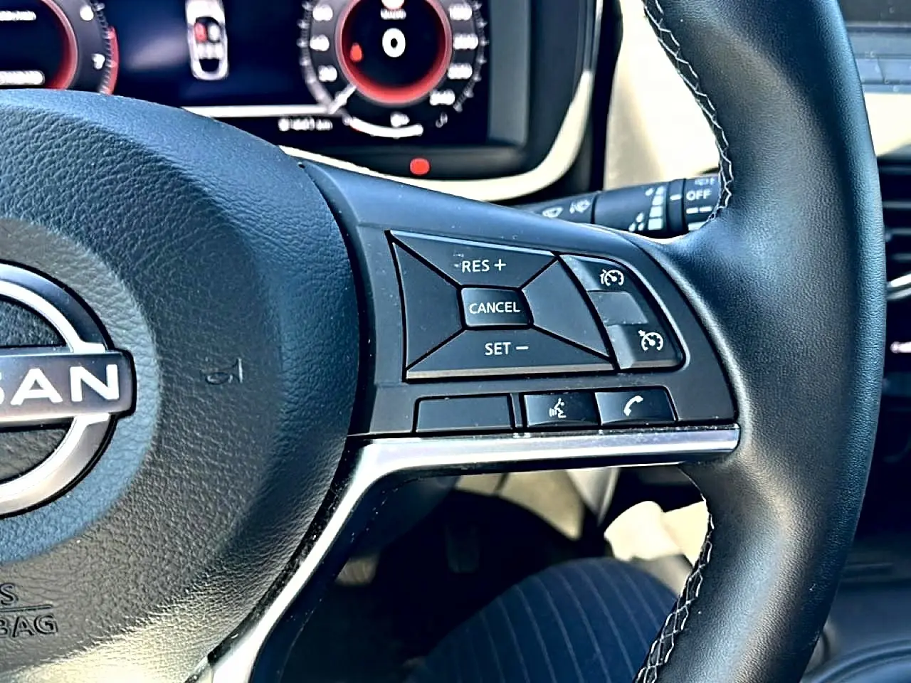 Gros plan sur le volant cuir noir du Nissan Juke 2025, avec commandes multifonctions visibles côté droit.