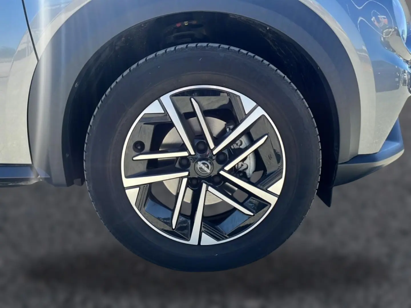 Gros plan sur la jante alu noire et argentée du côté avant droit du Nissan Juke gris 2025.