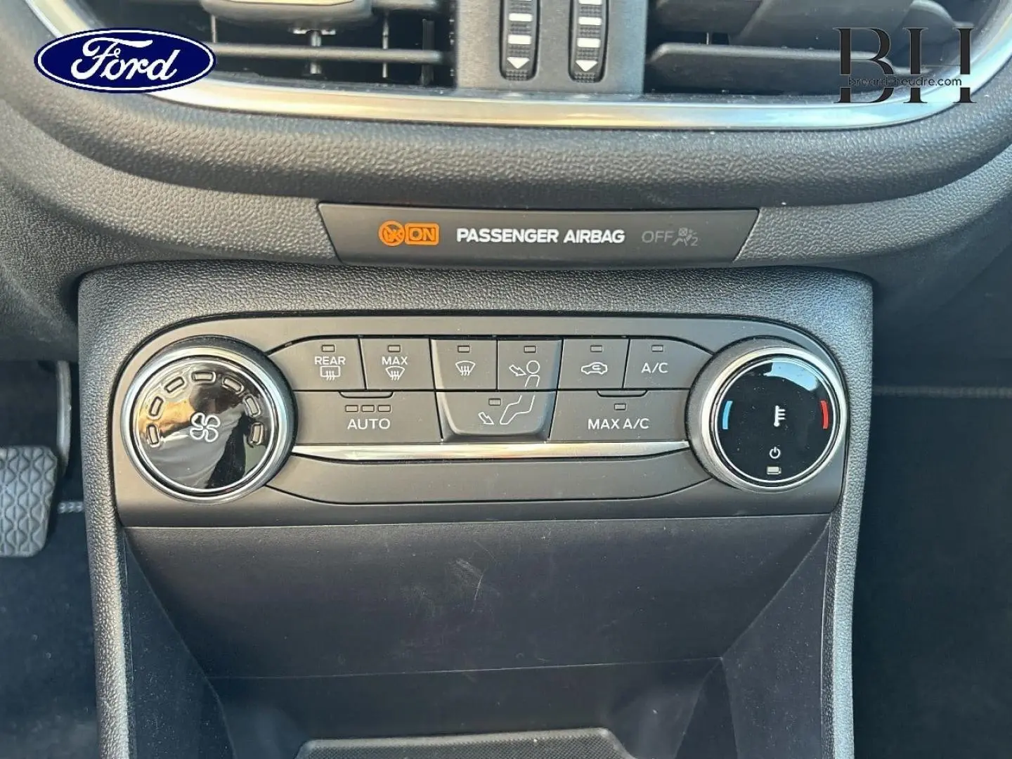 Vue rapprochée du tableau de bord noir de la Ford Fiesta 2023, montrant les commandes de climatisation et l'indicateur d'airbag passager.