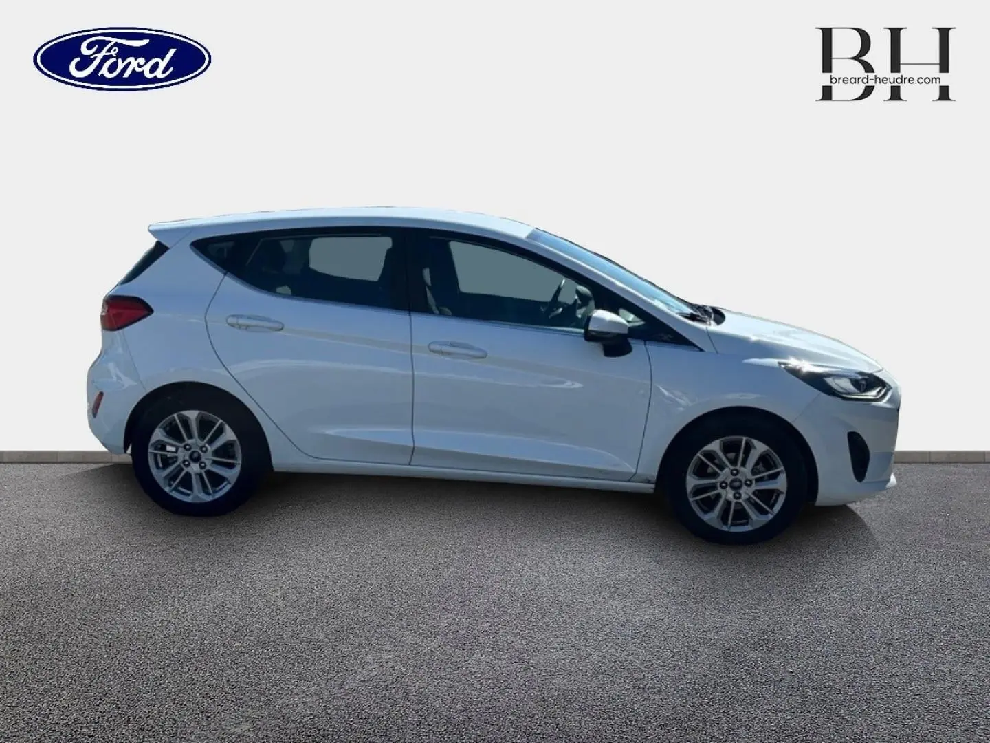 Profil droit d'une Ford Fiesta 2023 blanc glacier avec jantes alu et poignées ton carrosserie visibles.
