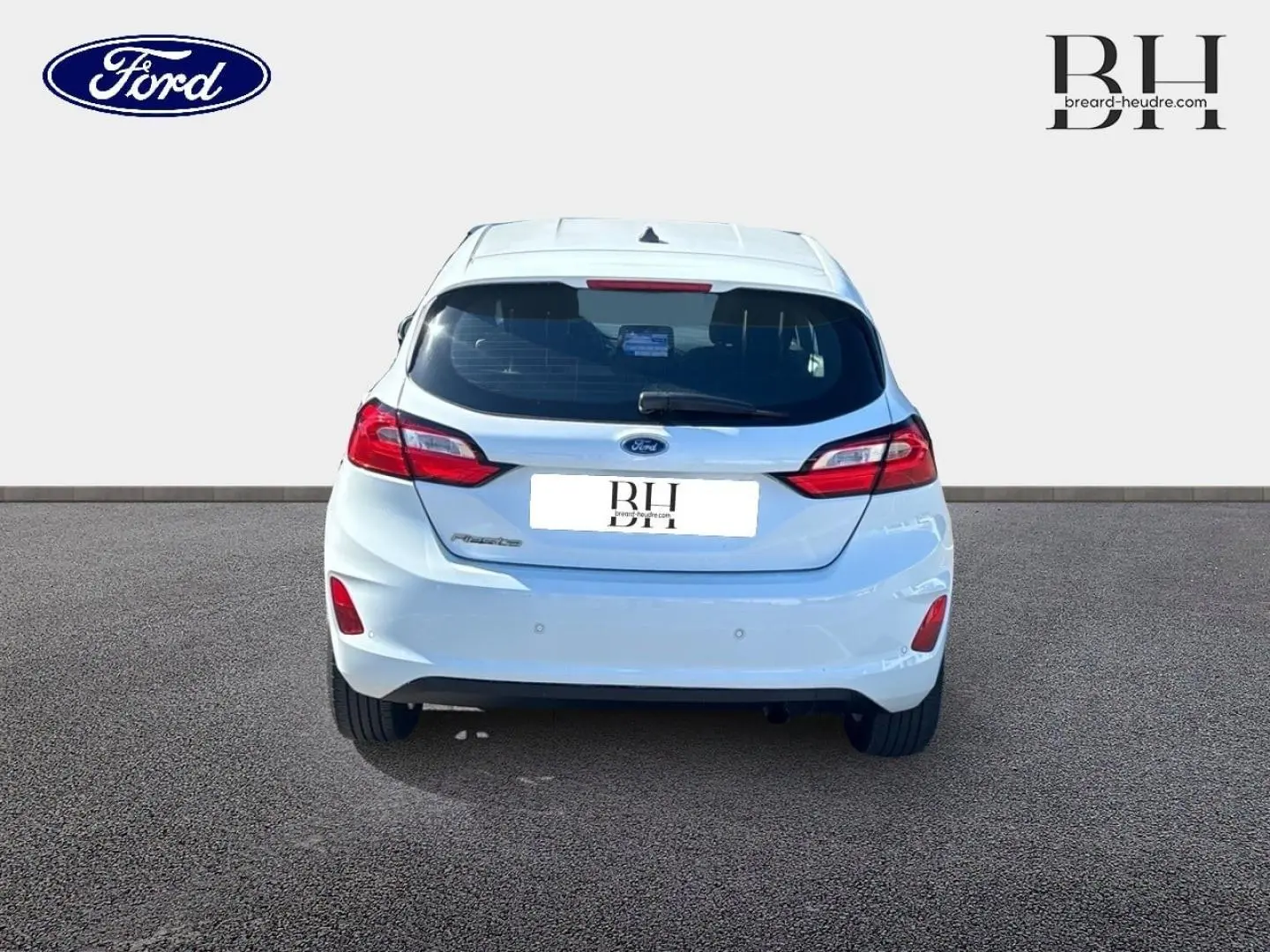 Vue arrière d'une Ford Fiesta blanc glacier 2023 avec feux LED et becquet arrière, sur sol goudronné.