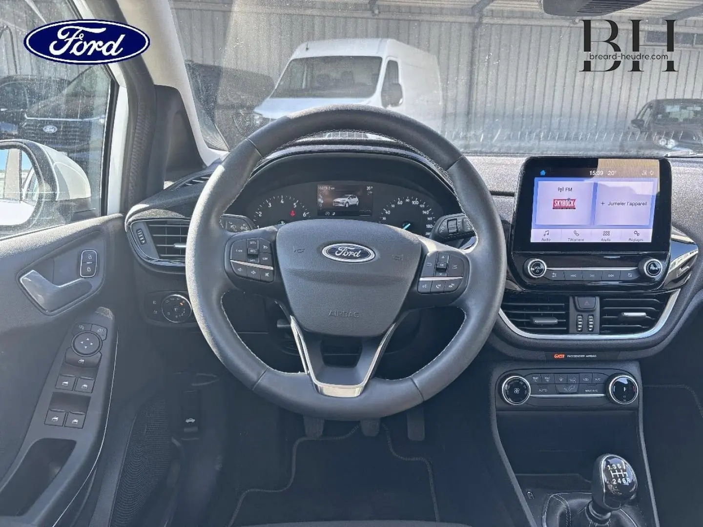 Vue intérieure centrée sur le volant cuir et tableau de bord avec écran tactile de la Ford Fiesta Titanium Business 2023.