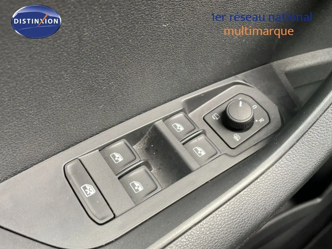 Gros plan sur les commandes des vitres et rétroviseurs électriques côté conducteur d’un Skoda Karoq blanc glacier.
