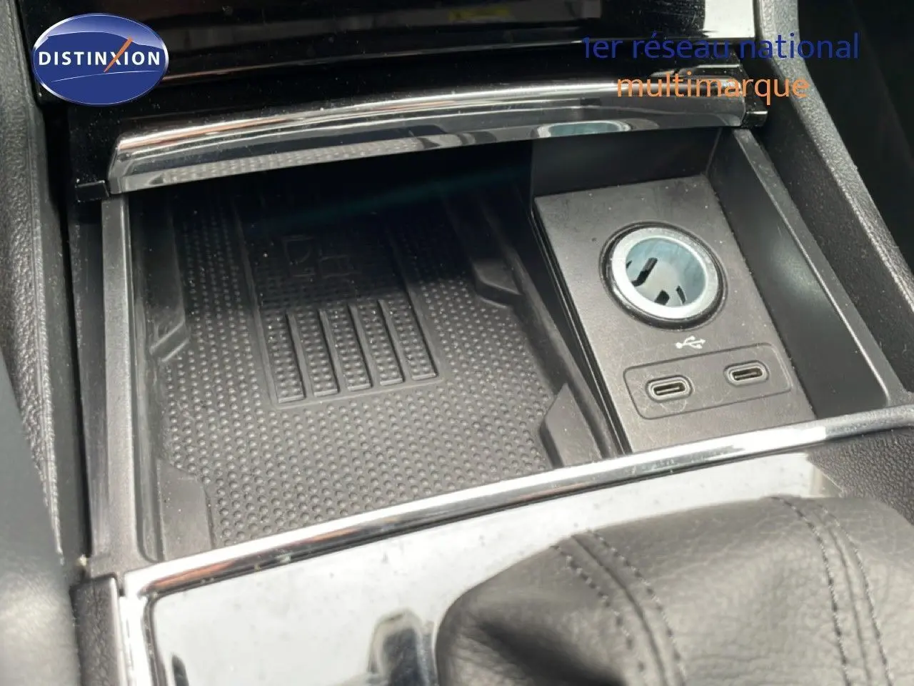 Gros plan sur la console centrale noire du Skoda Karoq avec prise USB et espace de rangement.