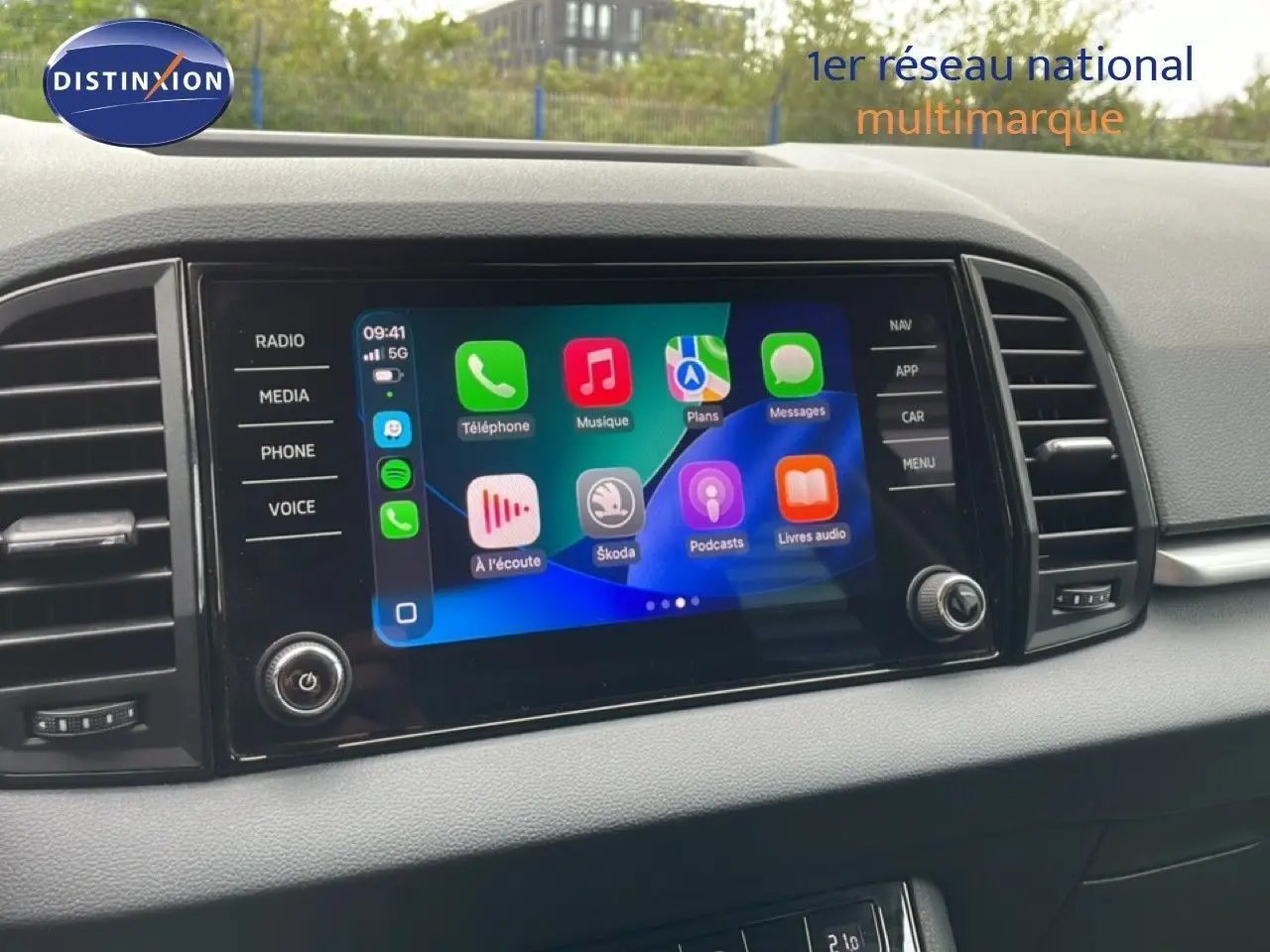 Écran tactile multimédia allumé dans l’habitacle noir du Skoda Karoq blanc, vue centrée sur la console centrale.