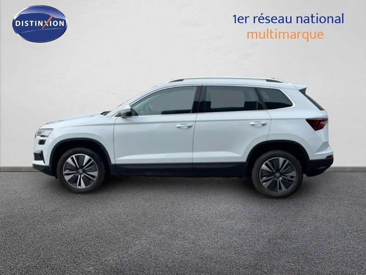 Profil droit d'un Skoda Karoq blanc glacier avec jantes bi-ton et vitres arrière surteintées.