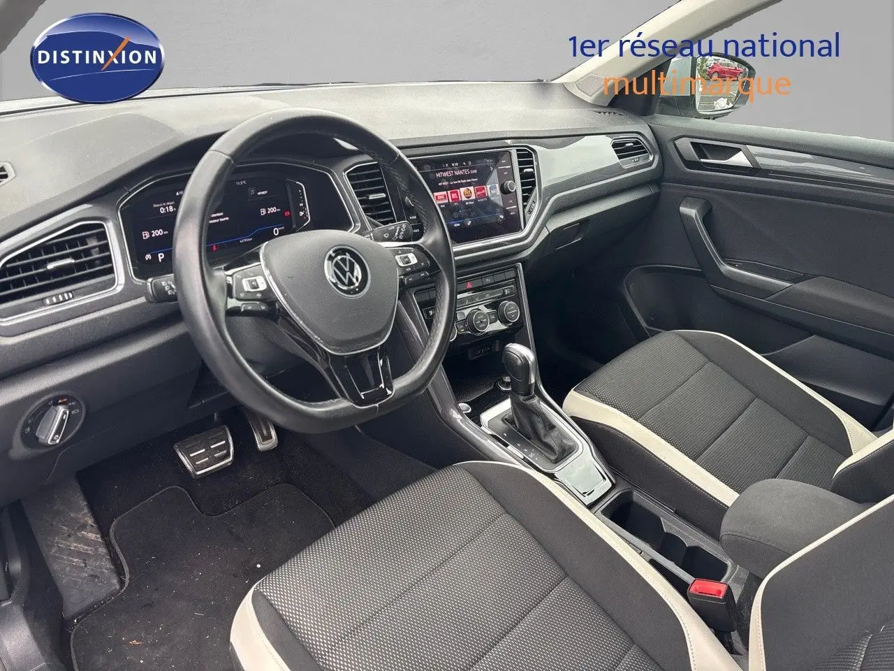 Vue intérieure côté conducteur du Volkswagen T-Roc 1.5 TSI 2021, avec tableau de bord numérique et sellerie noire à surpiqûres claires.