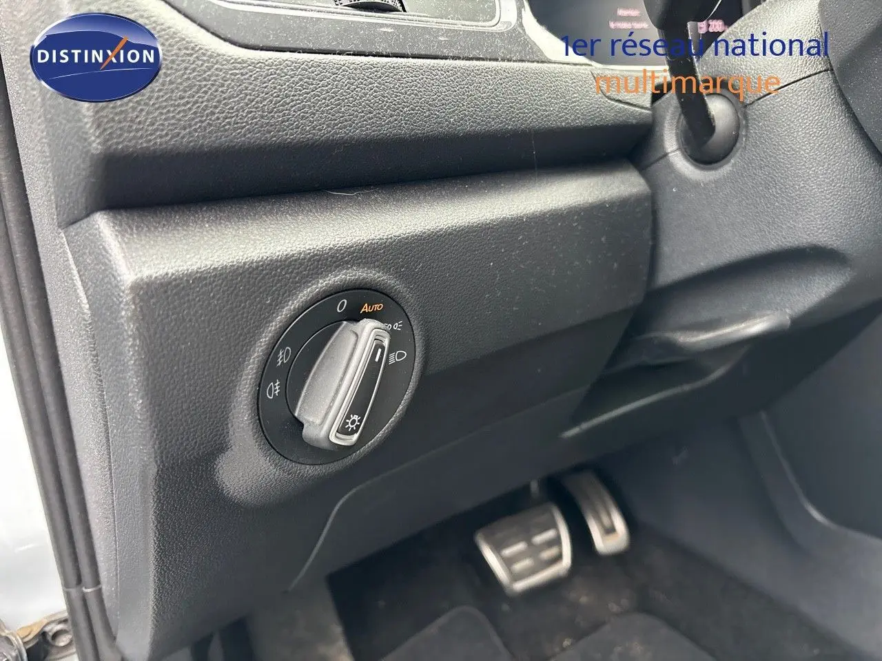 Gros plan sur le bouton de commande des phares à gauche du volant dans un Volkswagen T-Roc blanc argenté.