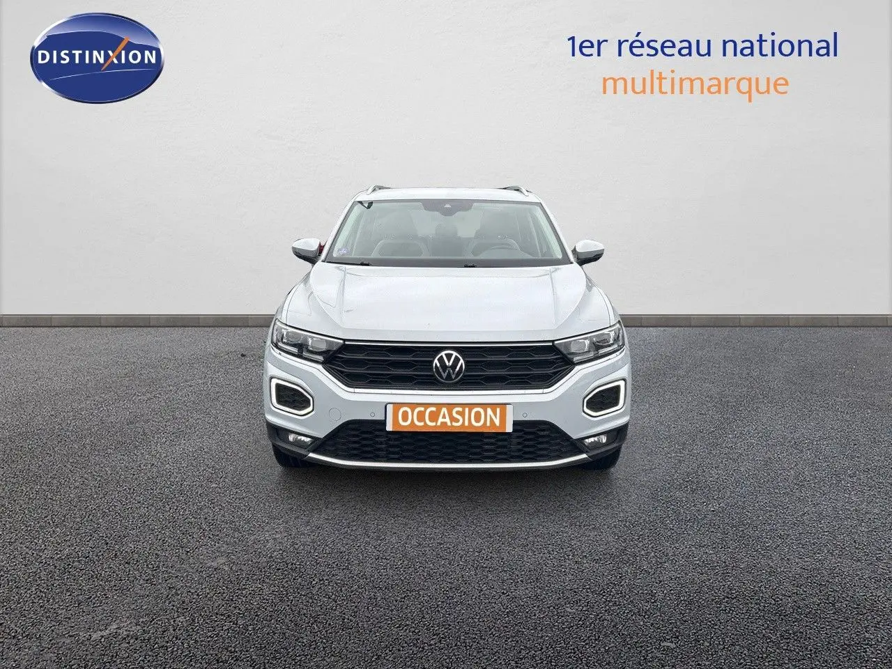 Volkswagen T-Roc blanc argenté vu de face, avec calandre noire et feux LED distinctifs allumés.