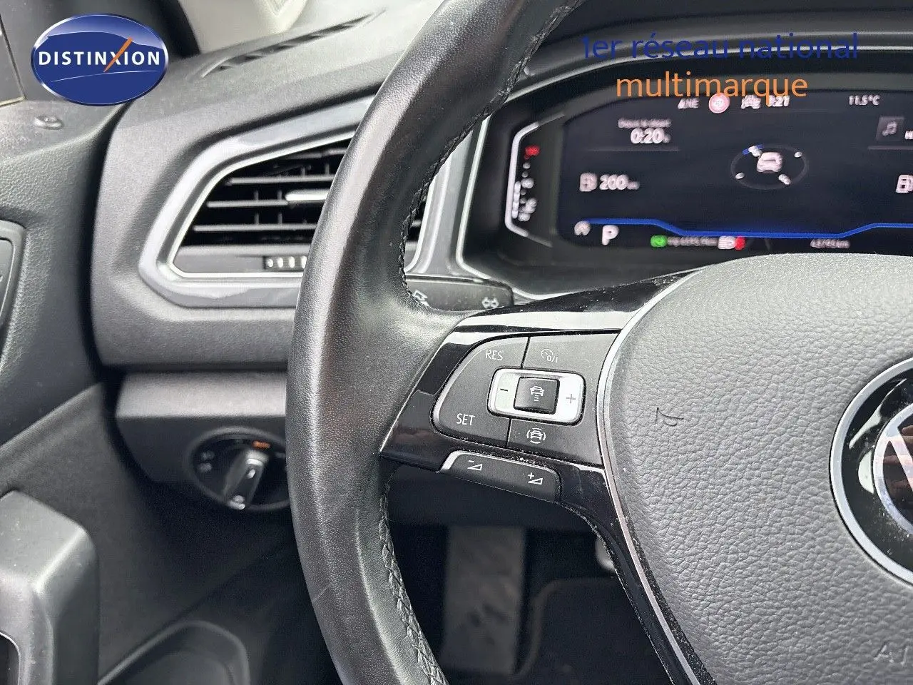 Gros plan sur le volant et le tableau de bord numérique du Volkswagen T-Roc 1.5 TSI blanc argenté, intérieur moderne.