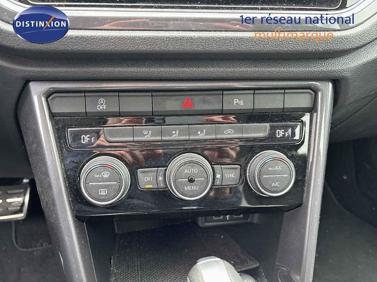 Gros plan sur la console centrale du Volkswagen T-Roc blanc, montrant les commandes de climatisation automatique et boutons de sécurité.