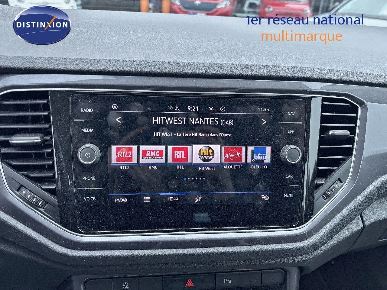 Tableau de bord du Volkswagen T-Roc blanc argenté, avec écran tactile affichant des stations radio numériques.