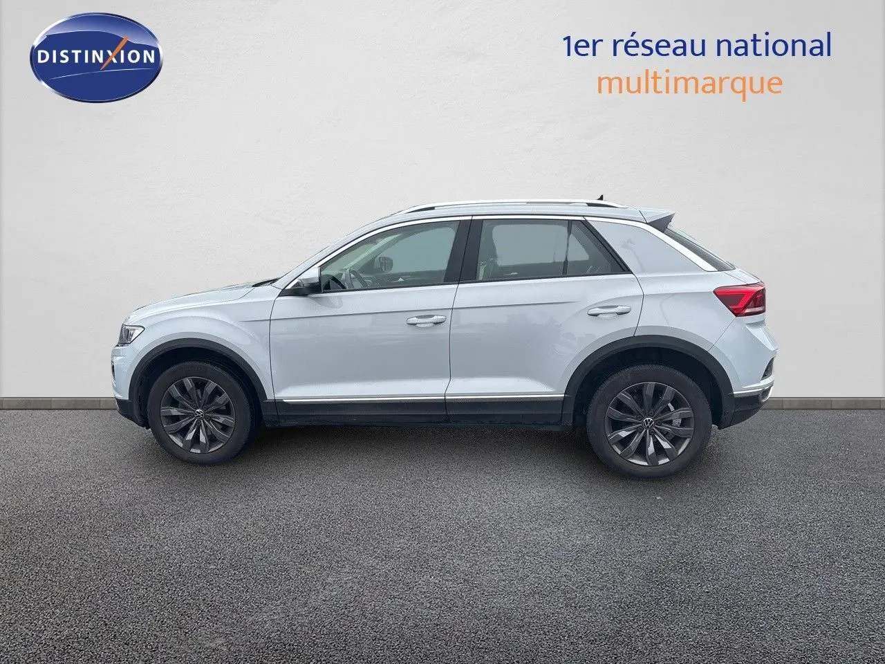 Profil côté gauche d'un Volkswagen T-Roc blanc argenté 2021 avec jantes foncées et toit ouvrant visible.